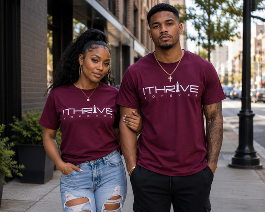 Two people wearing maroon 'ITHrive Forever' t-shirts on a city street.